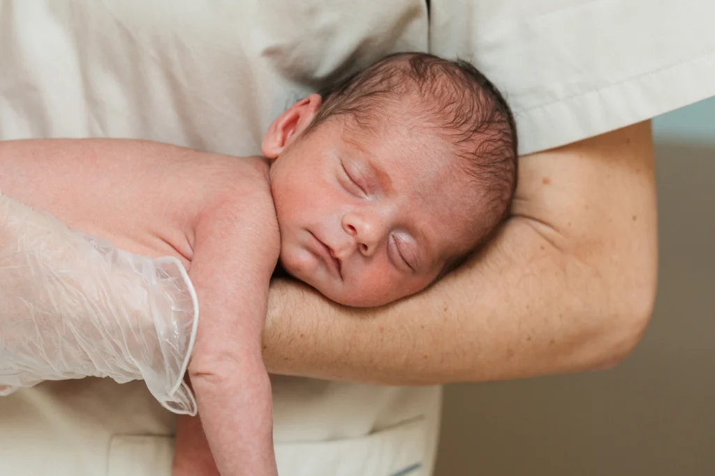 Close up view of a medical doctor holding on arms a newborn baby - A Complete Guide to Tylenol for Newborns - Kare One Support NICU Care