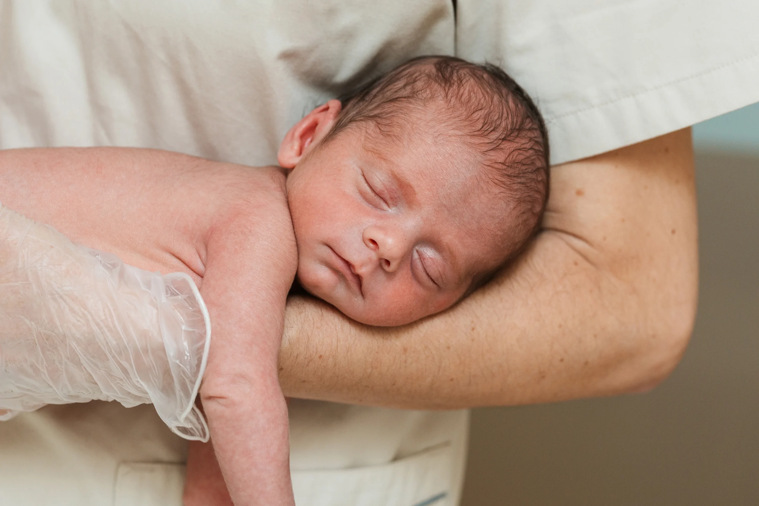 Close up view of a medical doctor holding on arms a newborn baby - A Complete Guide to Tylenol for Newborns - Kare One Support NICU Care