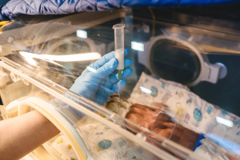 Nurse in neonatal intensive care unit carefully administers milk to a premature baby through a feeding tube - Neonatal Nutrition - Importance, Benefits & Myths - Kare One NICU Care